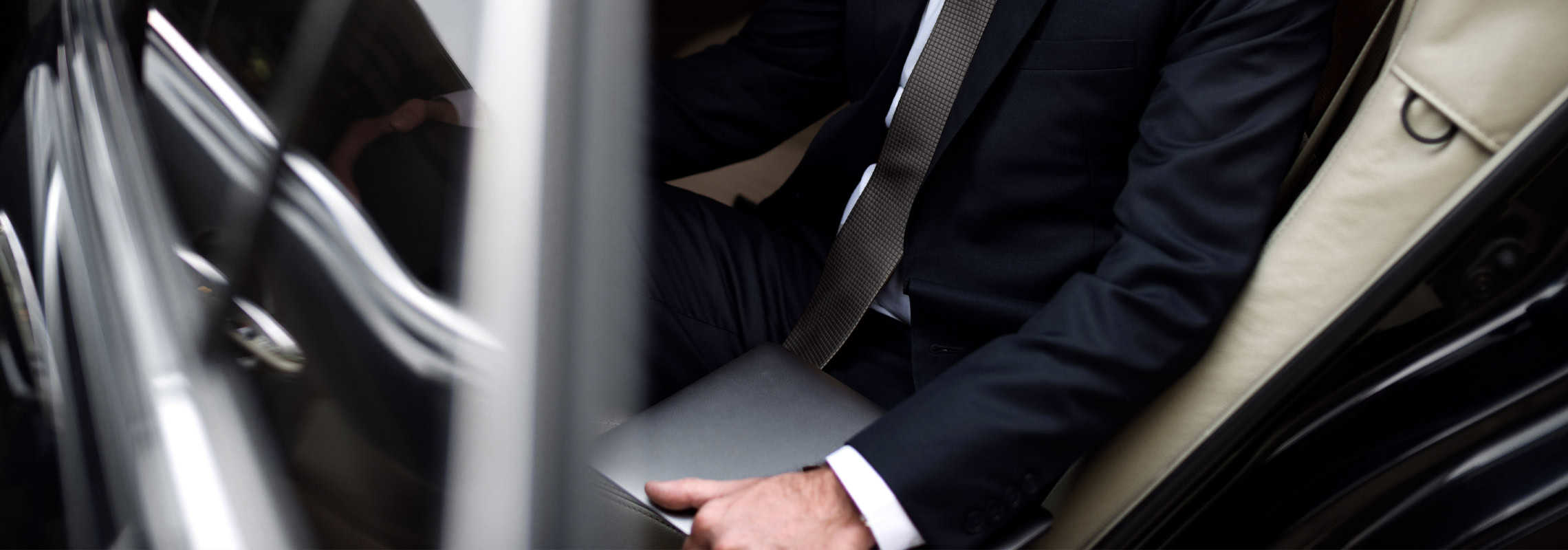 Smiling businessman talking on mobile phone in interior of business car. Luxury Car Rental Carleone limousine service in Bangkok, Thailand, offering premium airport transfer and chauffeured vehicles.
