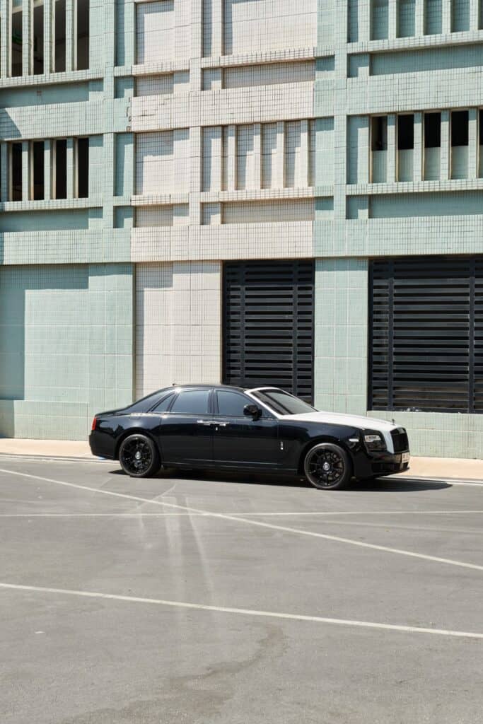 Black luxury car from Carleone parked in front of modern building in Bangkok, Thailand, showcasing premium limousine service and airport transportation options.